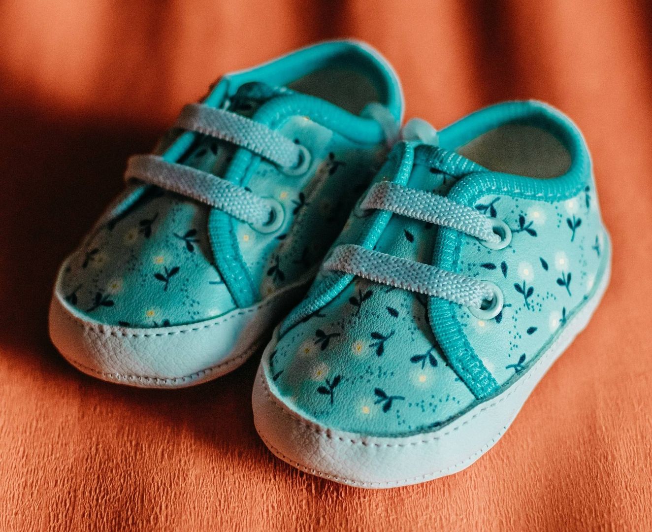 Blaue Babyschuhe auf orangenen Hintergrund