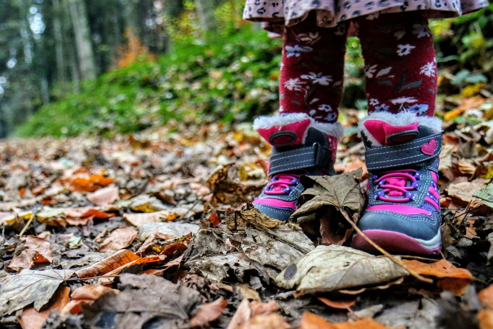 Kind mit Kinderstiefeln steht in einem Wald