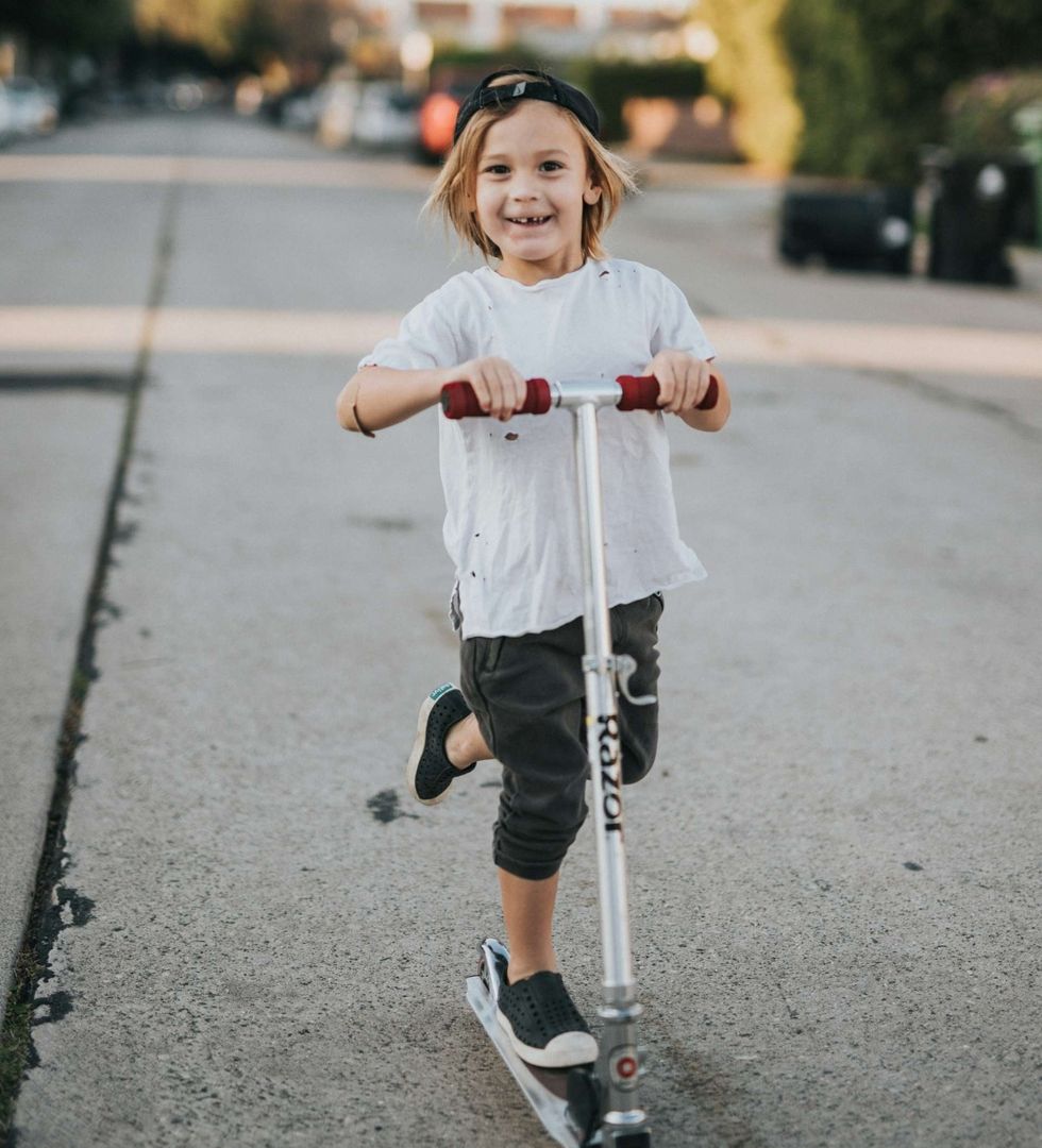 Kind fährt lachend auf einem Roller